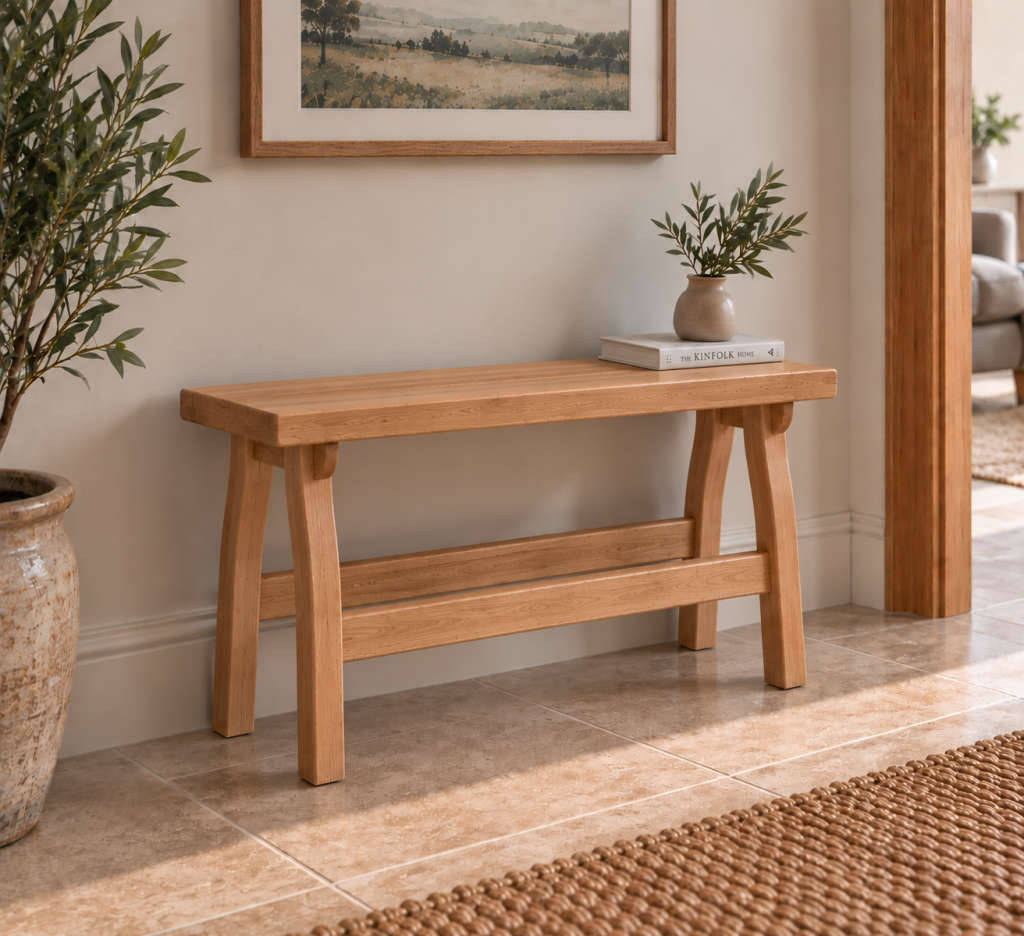 Uruz solid European oak bench with curved legs and natural Osmo Polyx Oil finish, styled against a wall in a warm modern hallway.