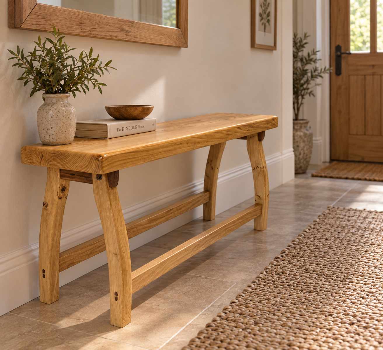 : Handcrafted Uruz solid oak hallway bench with curved legs and natural Osmo Polyx Oil finish, styled in a welcoming modern hallway.